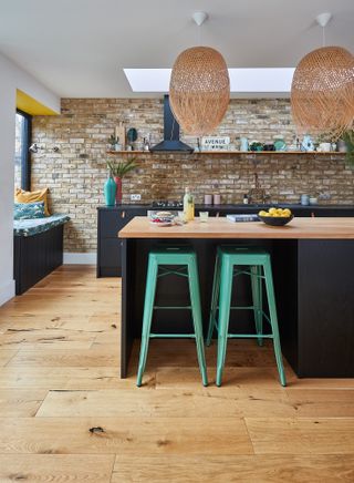 Lily Pickard house: kitchen island with dark wooden painted units and bright green industrial metal bar stools