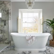 bathroom with freestanding bath, marble floor tiles and window with shutters