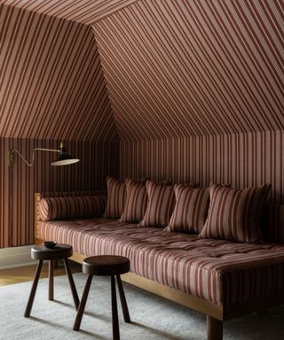 patterned drenched loft room with striped wallpapered all on walls including ceiling and bench sofa with matching striped fabric