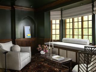 A living room with dark green walls and white armchairs