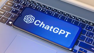 ChatGPT logo is seen displayed on a smartphone screen next to a laptop keyboard.