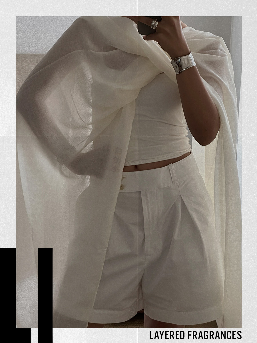A woman taking a mirror selfie of an all-white outfit with a sheer layered top