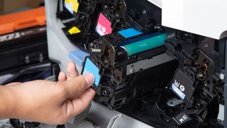 A technician inspecting a row of ink cartridges inside an office printer