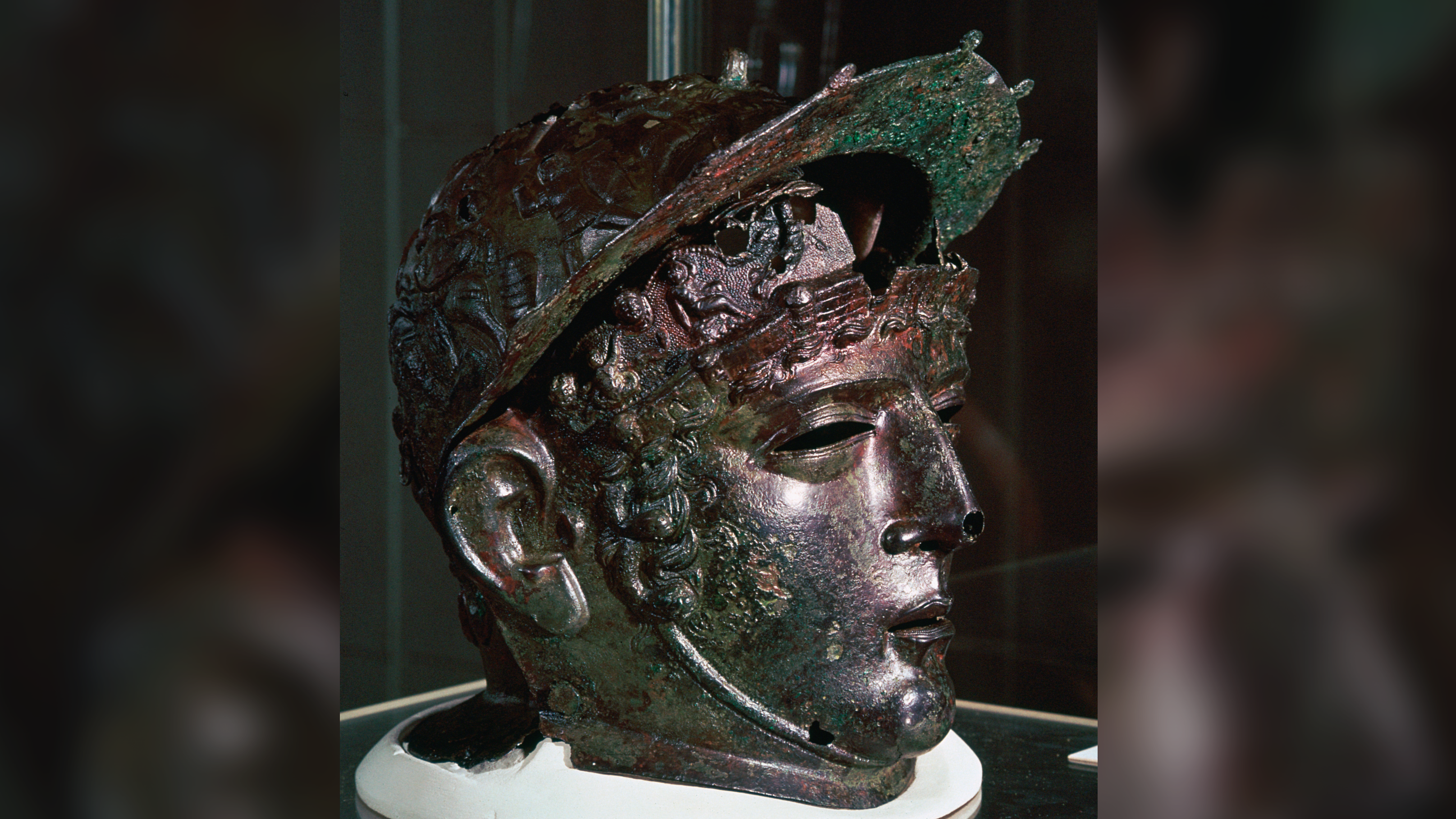 a greenish bronze helmet in the shape of a man's head and face