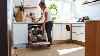 Woman loading dishwasher in kitchen