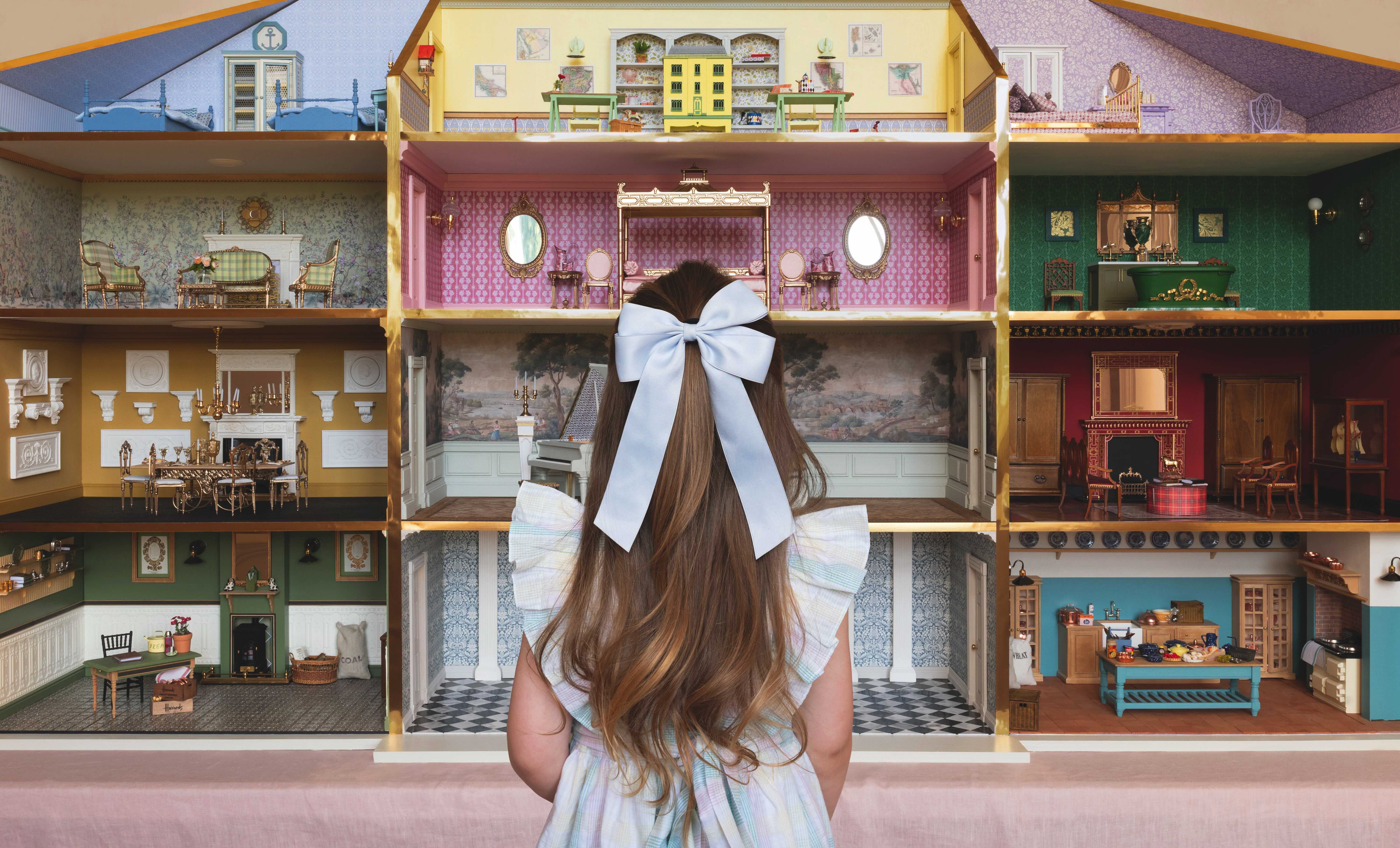 A young girl peers at a dolls house