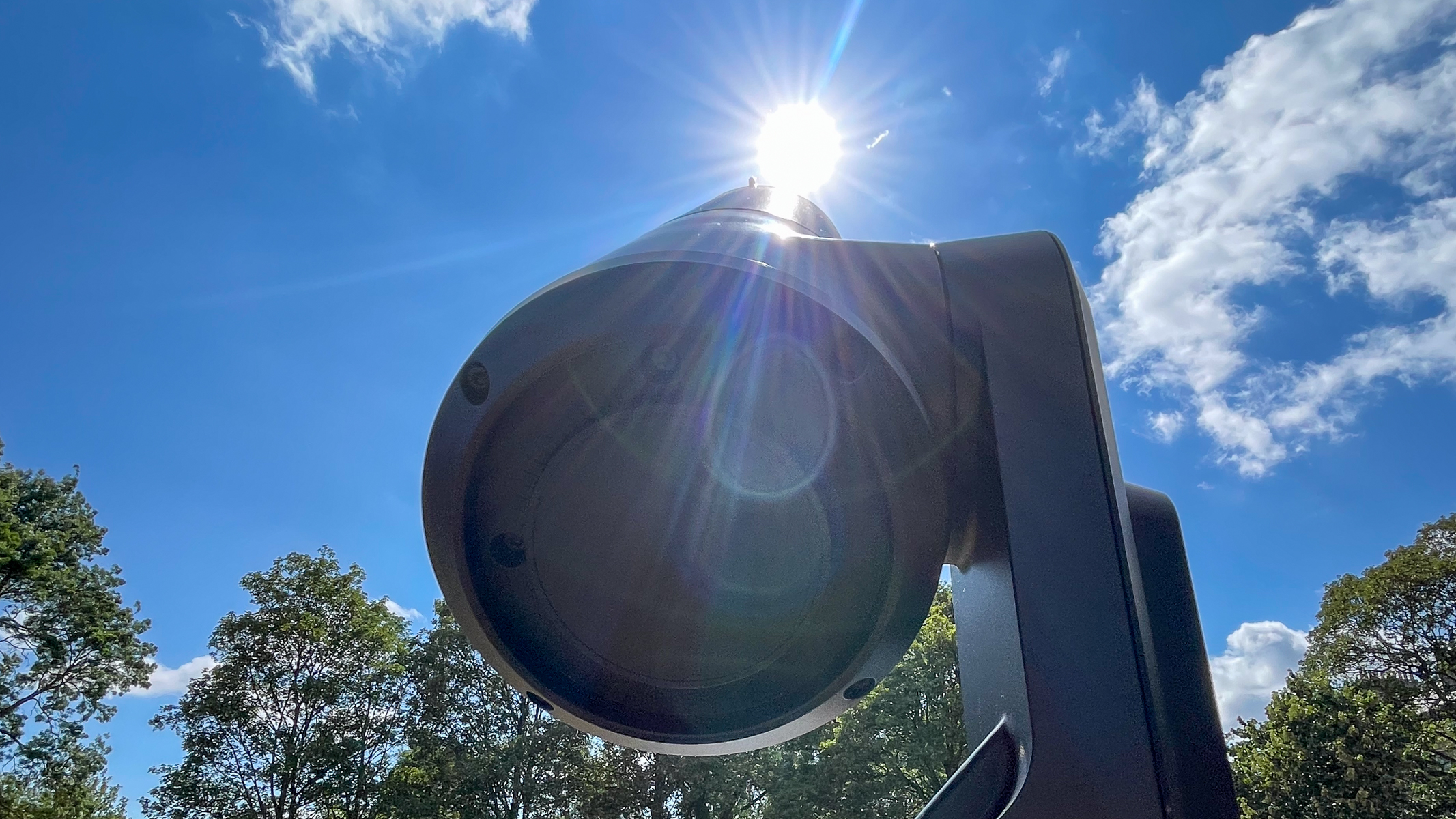 A Unistellar eVscope 2 pointing at the sun in the blue sky.