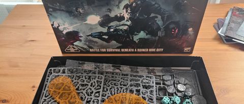 The Necromunda: Hive Secundus box and contents on a wooden table, with sprues and markers visible