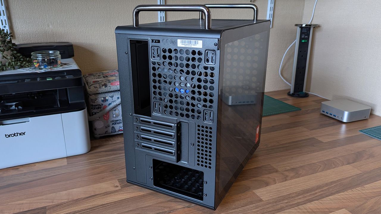 The rear of a Cooler Master Qube 340 case shows ventilation holes, expansion slots, and top carry handles, with a tempered glass side panel.