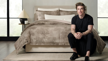 Jeremiah Brent sitting at the foot of a bed with a watercolor duvet color on the bed