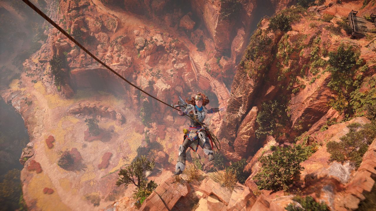 In-game screenshot of Aloy grappling off the side of a mountain in Horizon Forbidden West