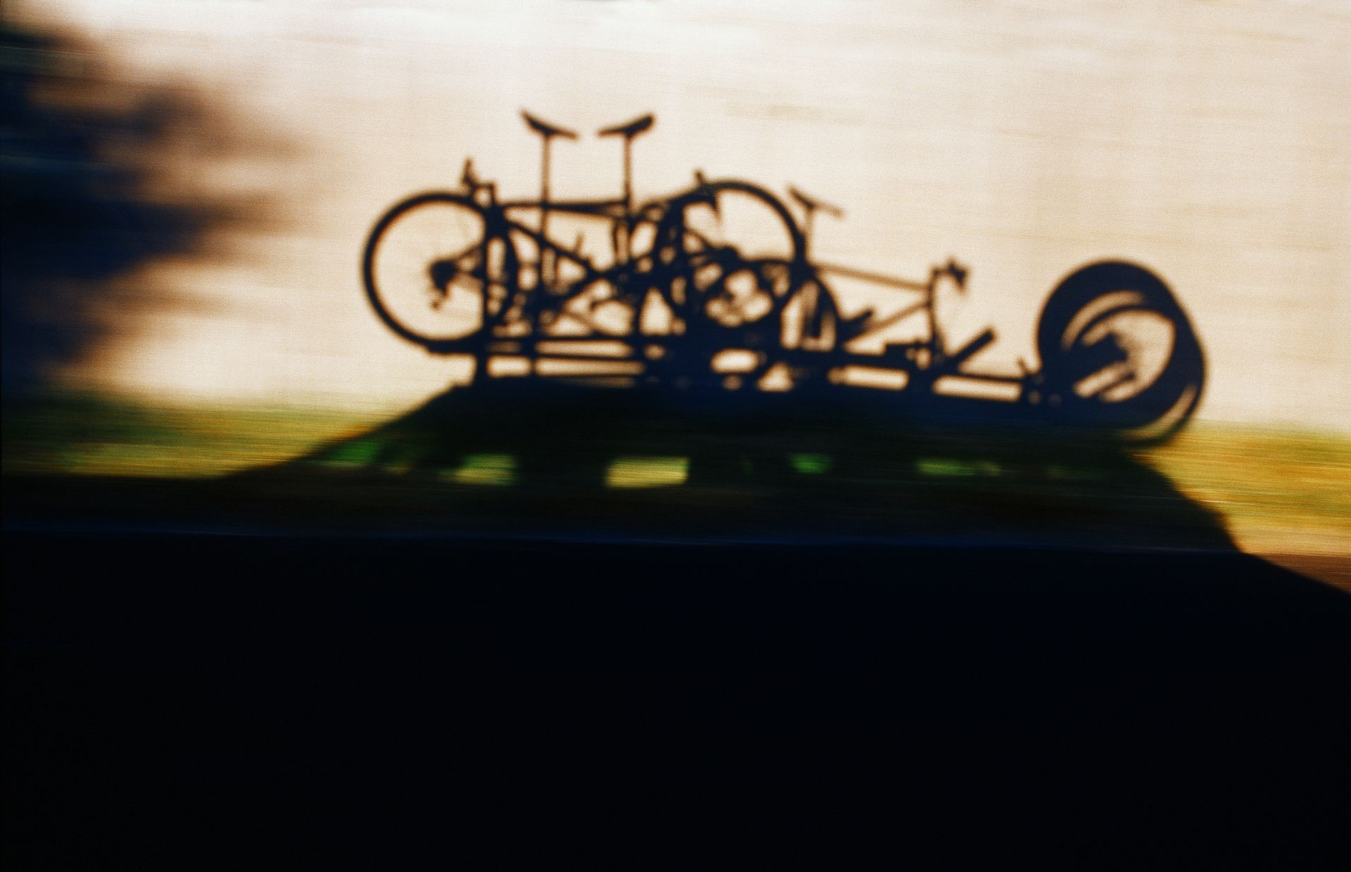 The shadows of three mountain bikes on a roof rack while on a Colorado road trip.