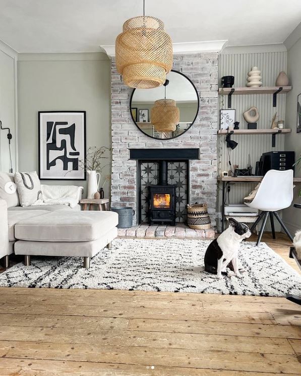 The living room with a small dog in the foreground of the image and logburner lit