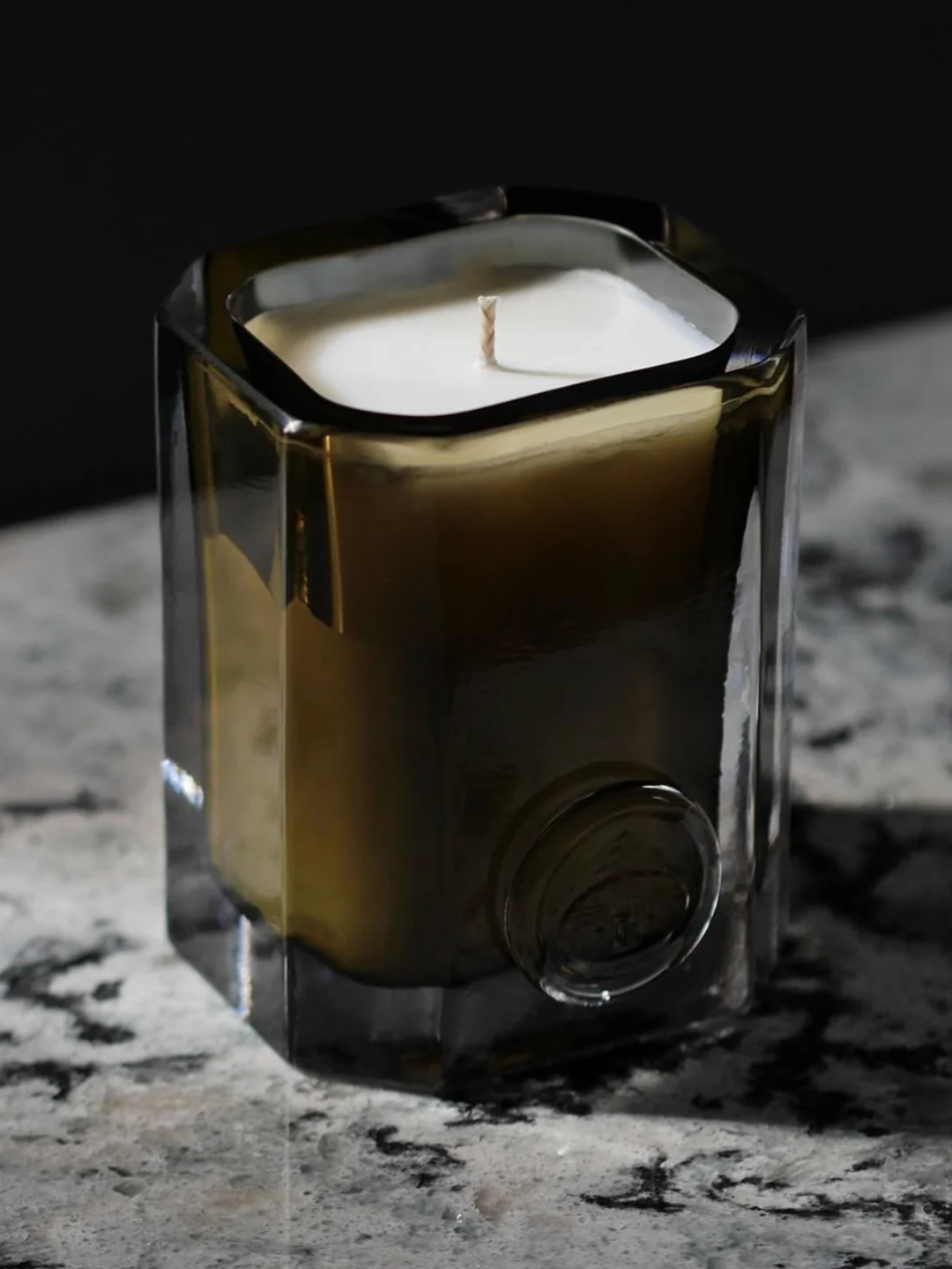 A green glass candle on a stone surface from ENYALY&amp;Euml;