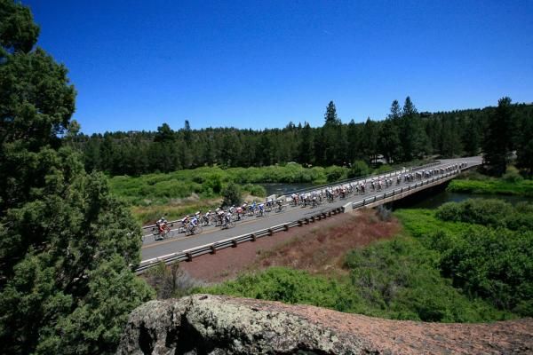 The peloton crosses over a scenic bridge.