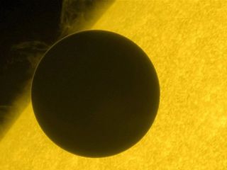 A dark circle in front of a giant glowing sun.