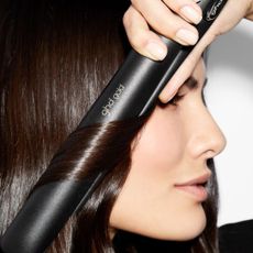 ghd deals - woman curling her hair with the ghd gold striaghteners