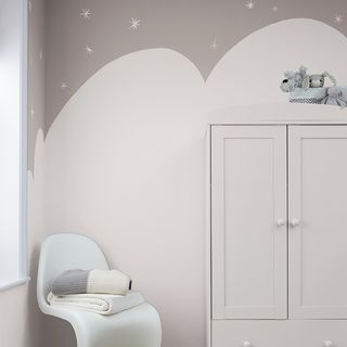 Cloudscape painted design in grey and white on walls, behind white chair and wardobe