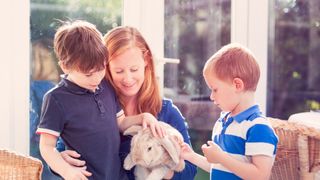 Woman and two children stroking a rabbit