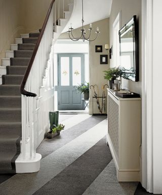A hallway carpet idea with diagonal grey striped carpet and blue front door