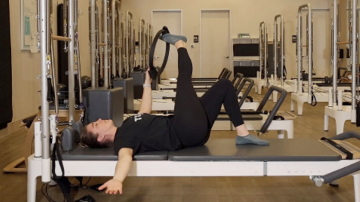 Woman on a Reformer Pilates machine demonstrating an exercise