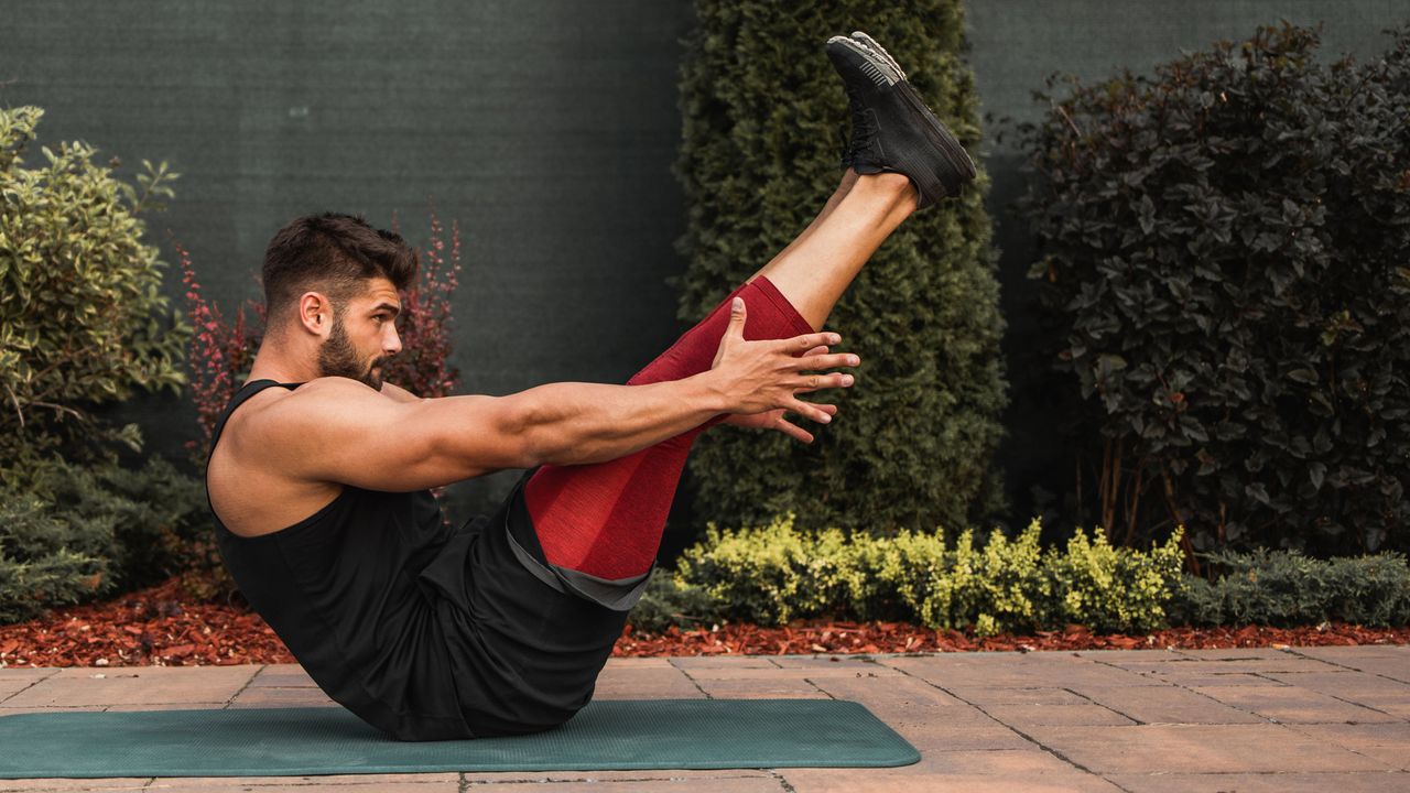 Man doing Pilates workout outside on yoga mat