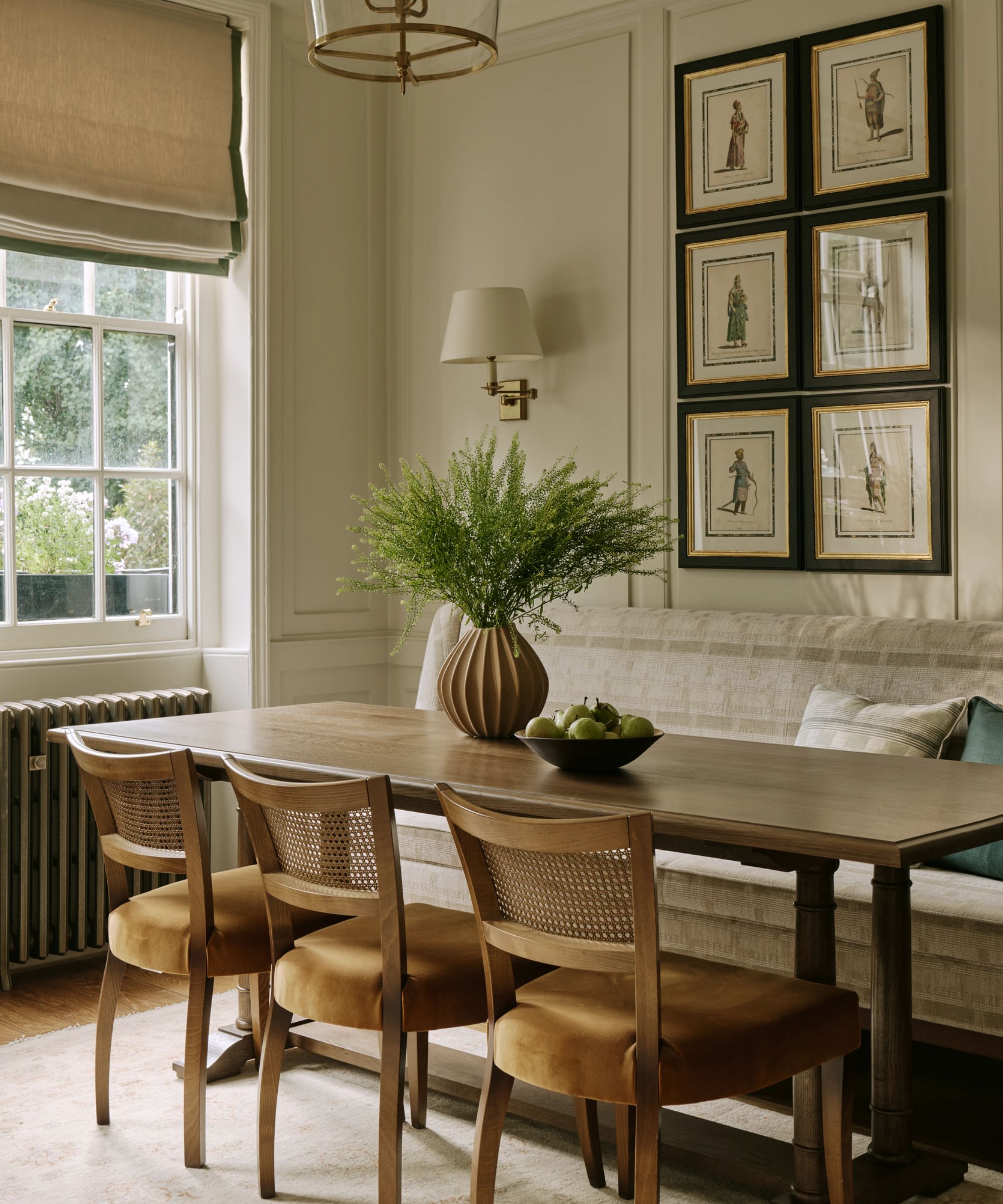 a calm dining room in london with large georgian window and paneled walls, a banquette seat with antique wooden table and chairs