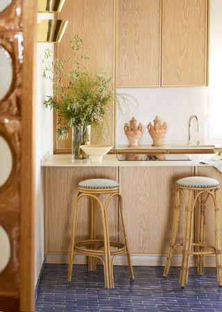 Blue kitchen flooring tiles with bight oak cabinets and bar stools.