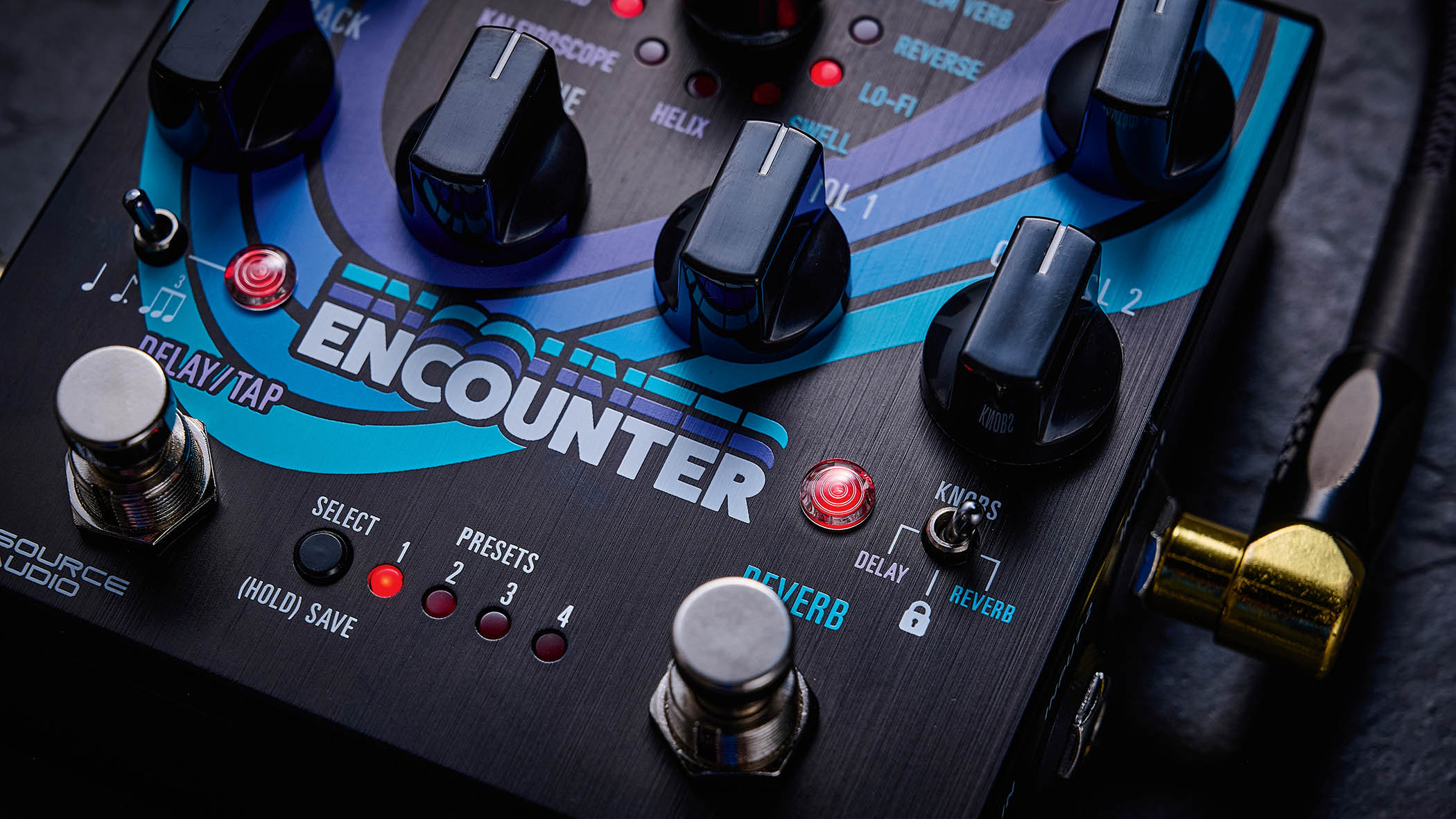 The Source Audio Encounter delay and reverb pedal is photographed here in close-up against an industrial metal background.