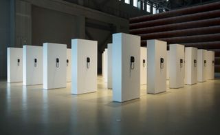 Five rows of white cube boxes that each have a telephone attached to them in the centre.