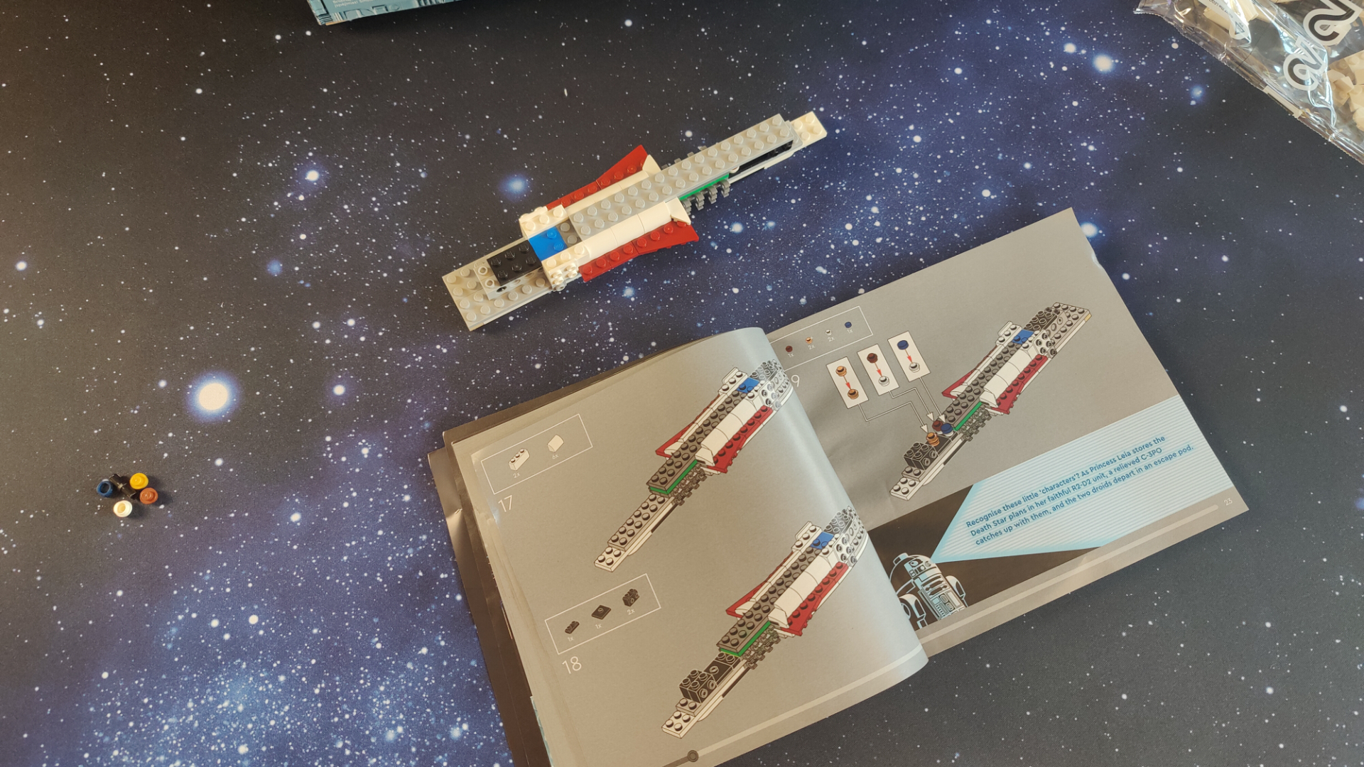 Lego Tantive IV set in pieces on a starry background, with the instructions open below it