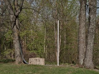 Lawn with trees and forest in the background with steel and stone sculptural install