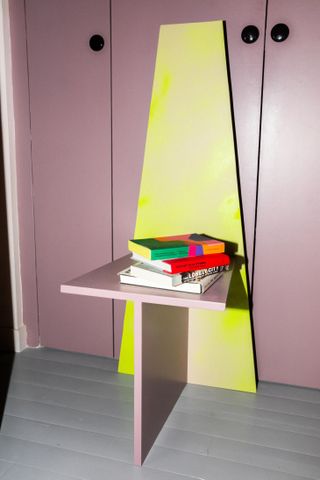 Purple walls, wall table with books on.