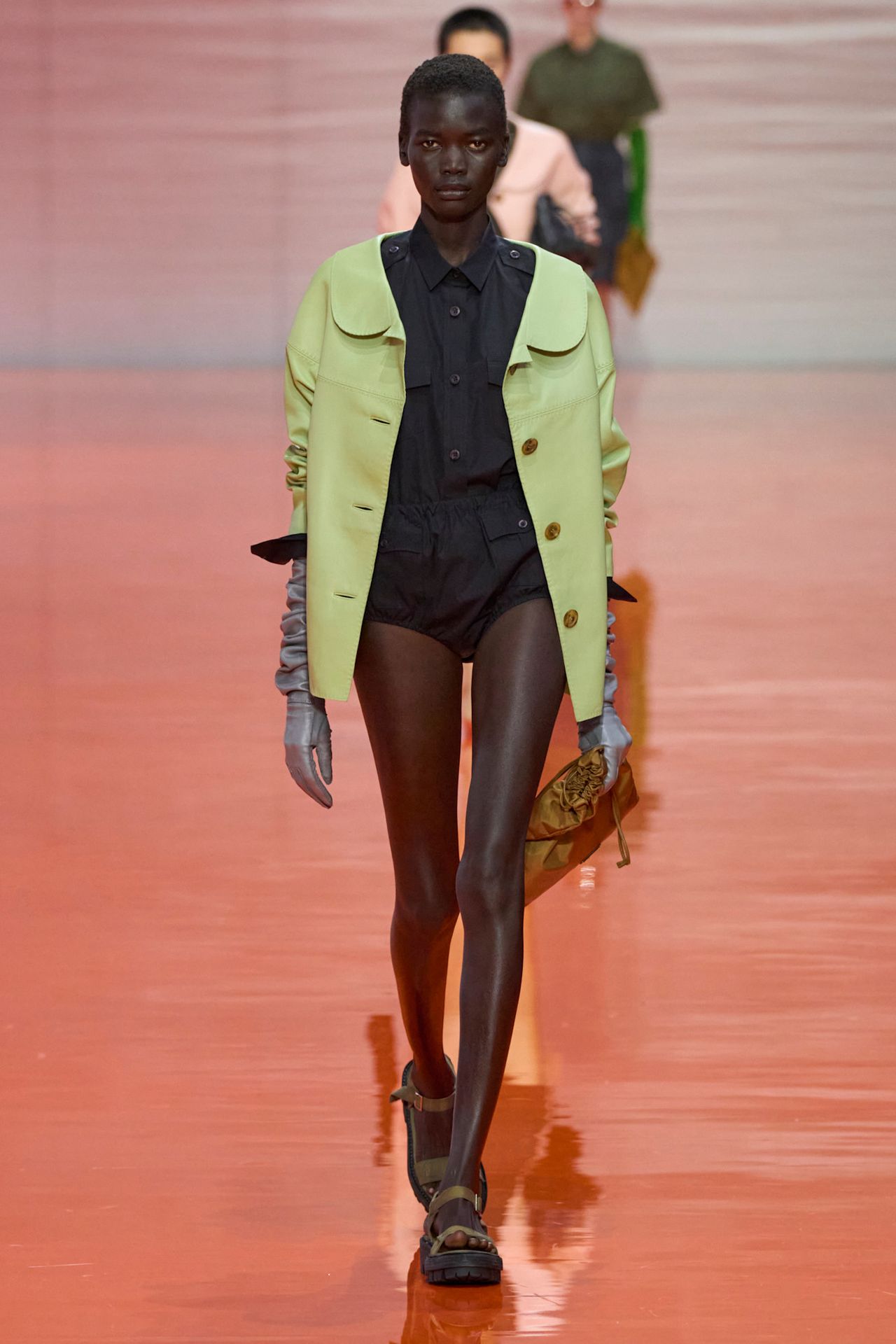 A model at the SS26 Prada show in Milan wearing a green jacket.