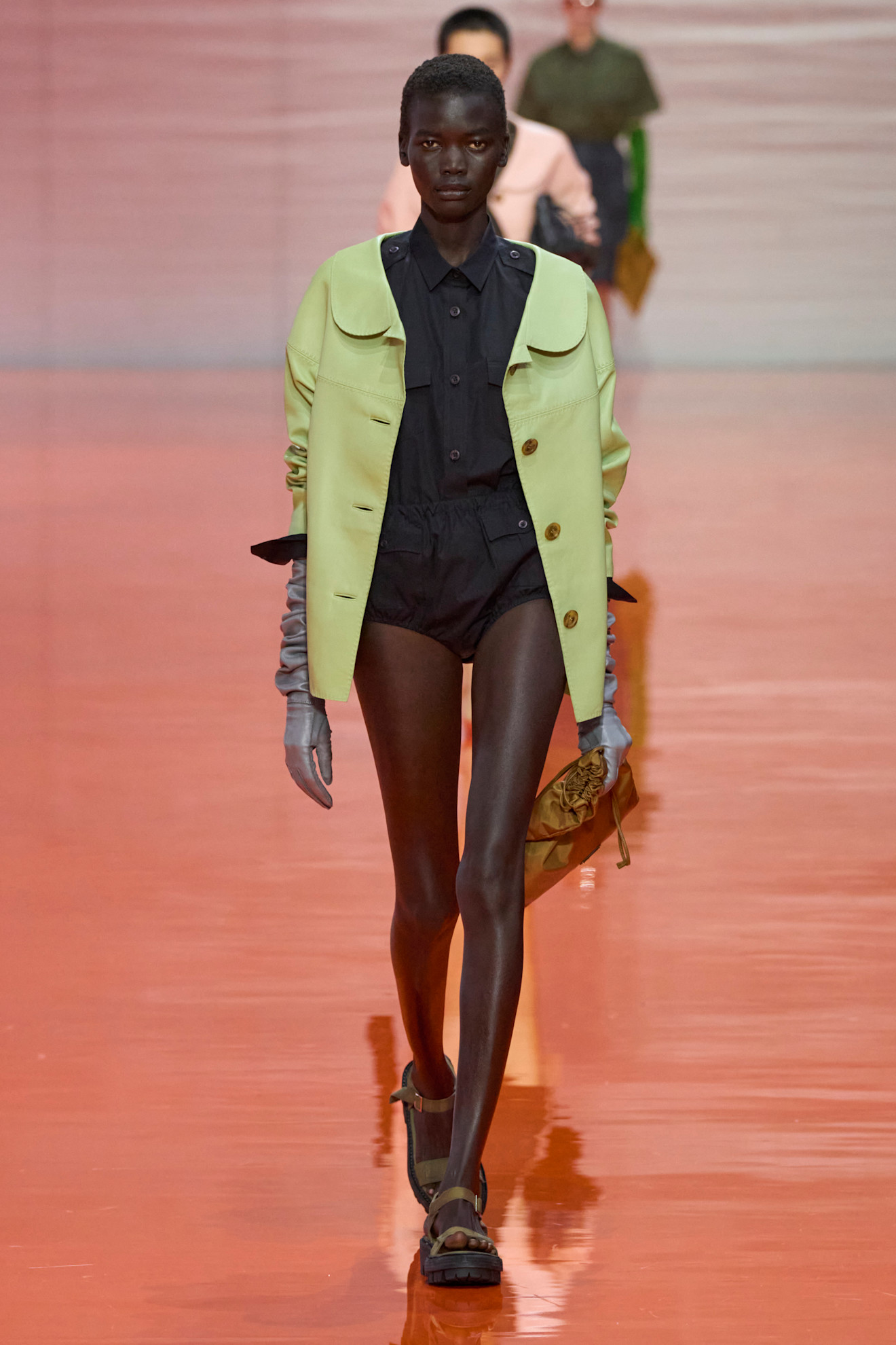 A model at the SS26 Prada show in Milan wearing a green jacket. 