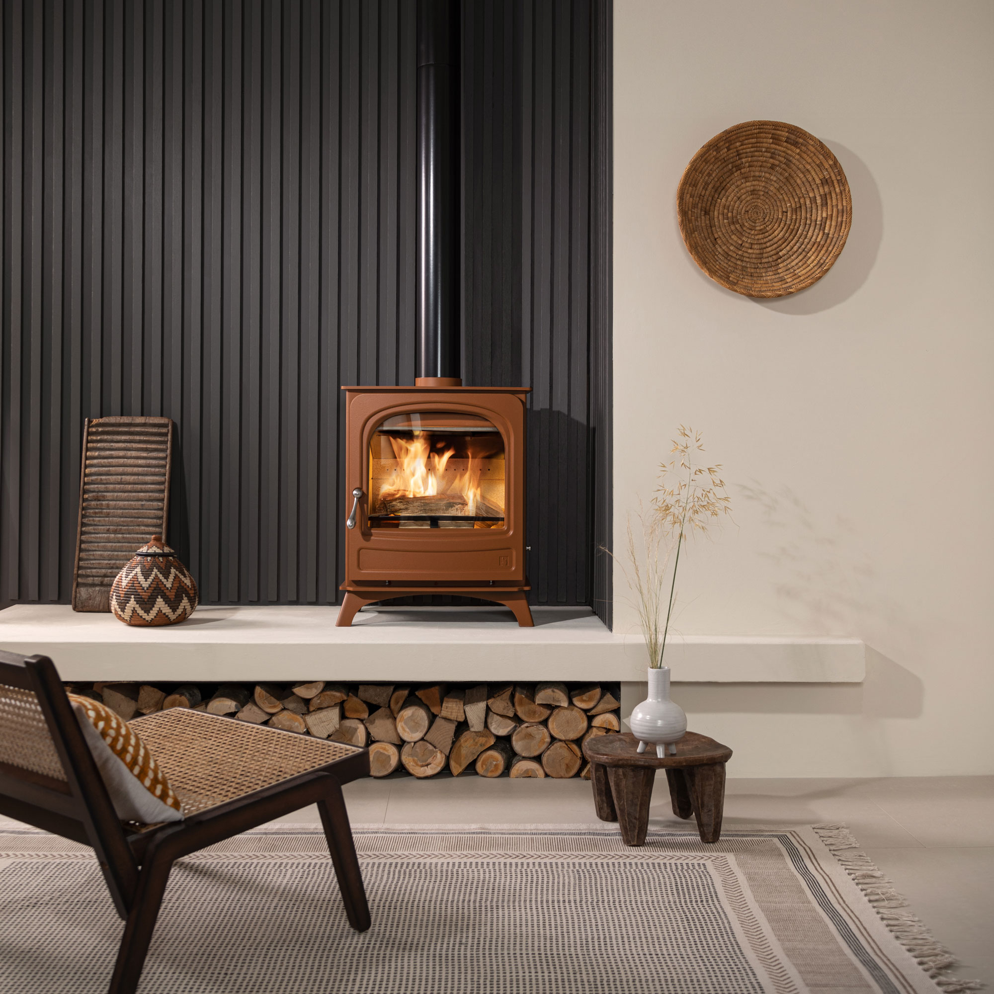 modern terracotta log burning stove on modern raised hearth with log storage beneath