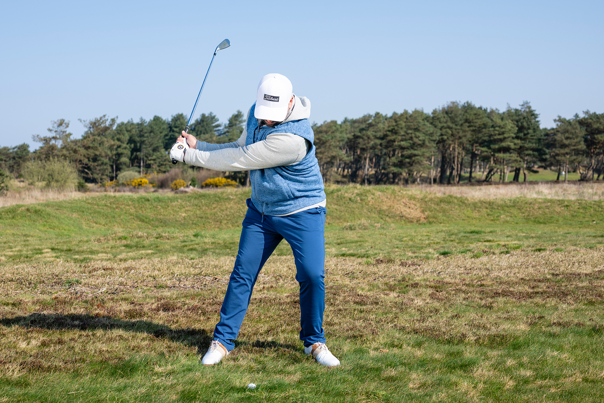 Peter Finch demonstrating 3 key adjustments when hitting the ball out of long rough, including ball position further back, weight on lead side and quick wrist hinge in the golf swing