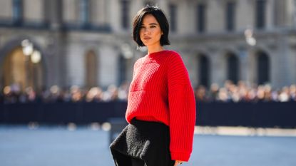 A guest wearing yellow sweater, skirt, and sunglasses on Paris Fashion Week Spring/Summer 2024