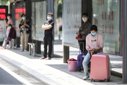 People wait at a bus station in Wuhan on May 11, 2020