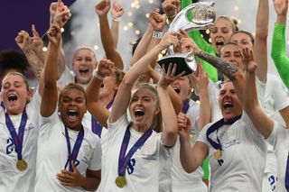 England's midfielder Leah Williamson (C) and England's defender Millie Bright (R) lift the trophy as England's players celebrate after their win in the UEFA Women's Euro 2022 final football match between England and Germany at the Wembley stadium, in London, on July 31, 2022. England won a major women's tournament for the first time as Chloe Kelly's extra-time goal secured a 2-1 victory over Germany at a sold out Wembley on Sunday.