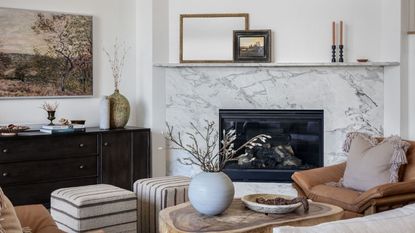 A white living room filled with decor clustered in groups on a coffee table, fireplace, and side board