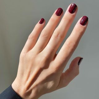 Hand with shiny, burgundy-red nail polish