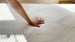 A hand pressing down on the Silentnight Lift Replenish Hybrid 2000 mattress