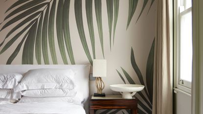 Palm leaf mural behind white bed