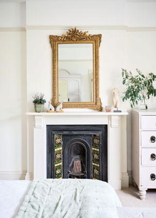 original bedroom fireplace with mirror above in room with green bedcover