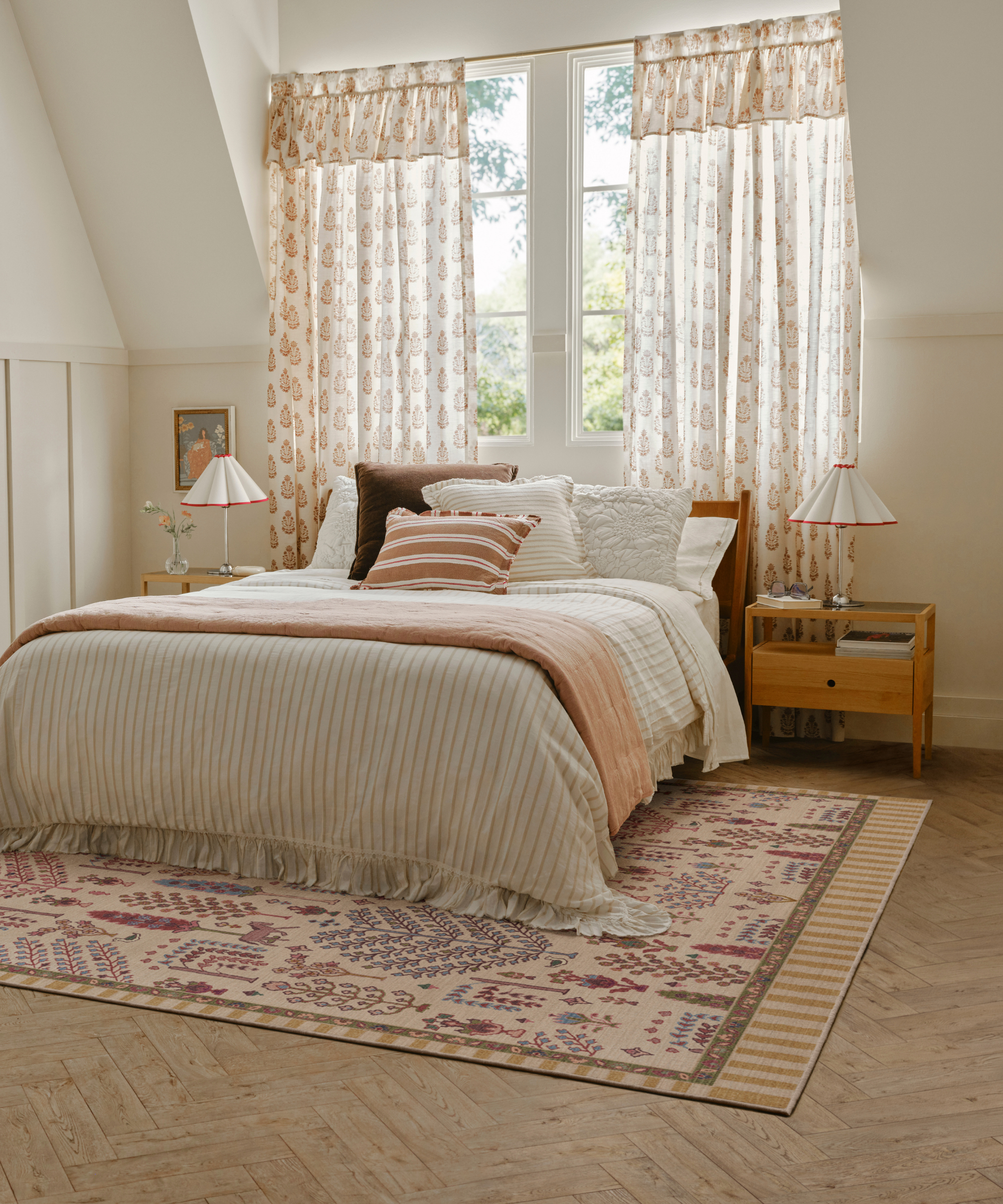 a bedroom with large windows, a bed with striped sheets, and a printed rug on the floor