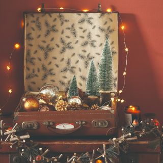 An old suitcase used as a Christmas decor display durrounded by fairy lights