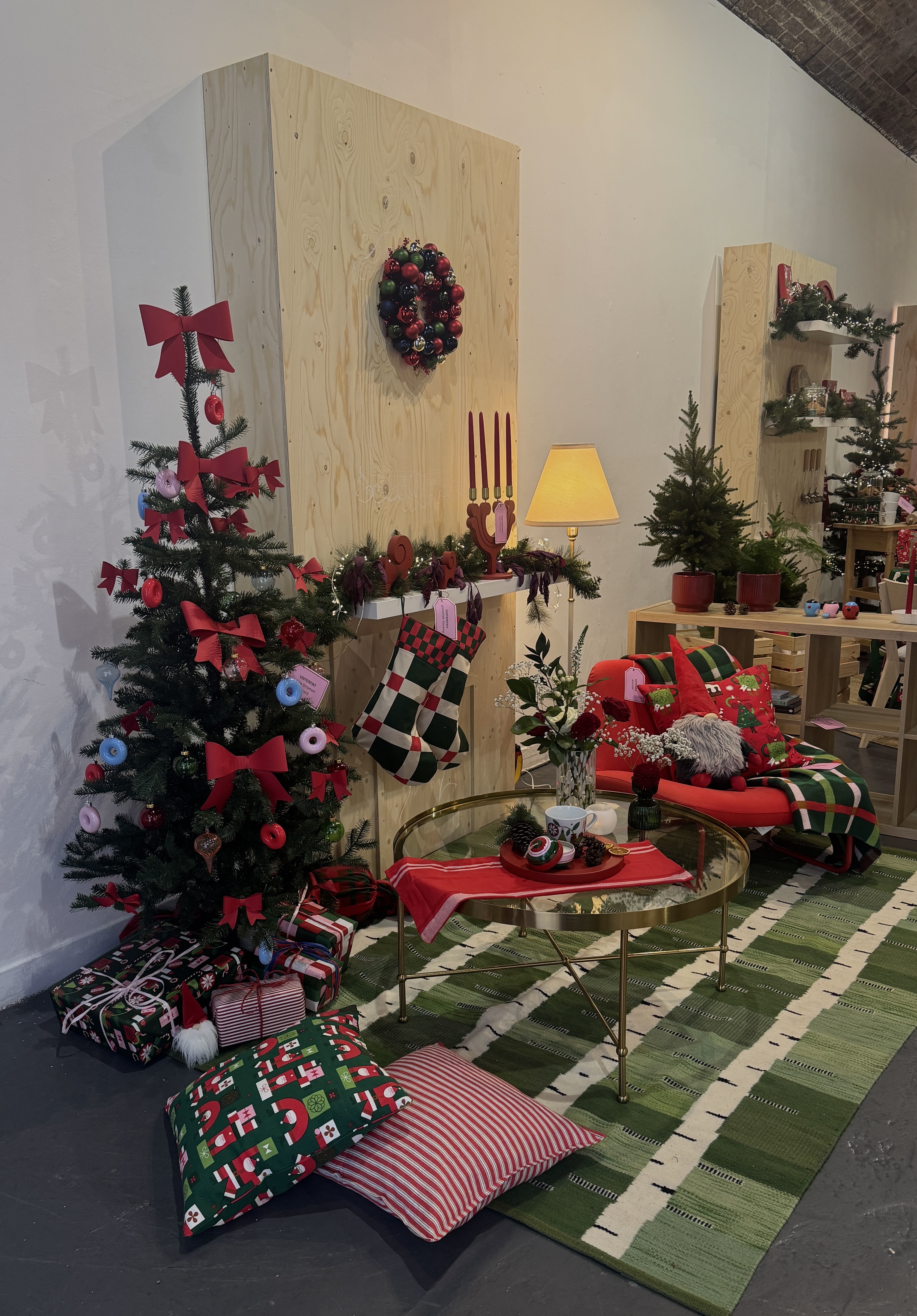 IKEA christmas collection with tree, green rug, patterned cushions, coffee table, stockings, and presents
