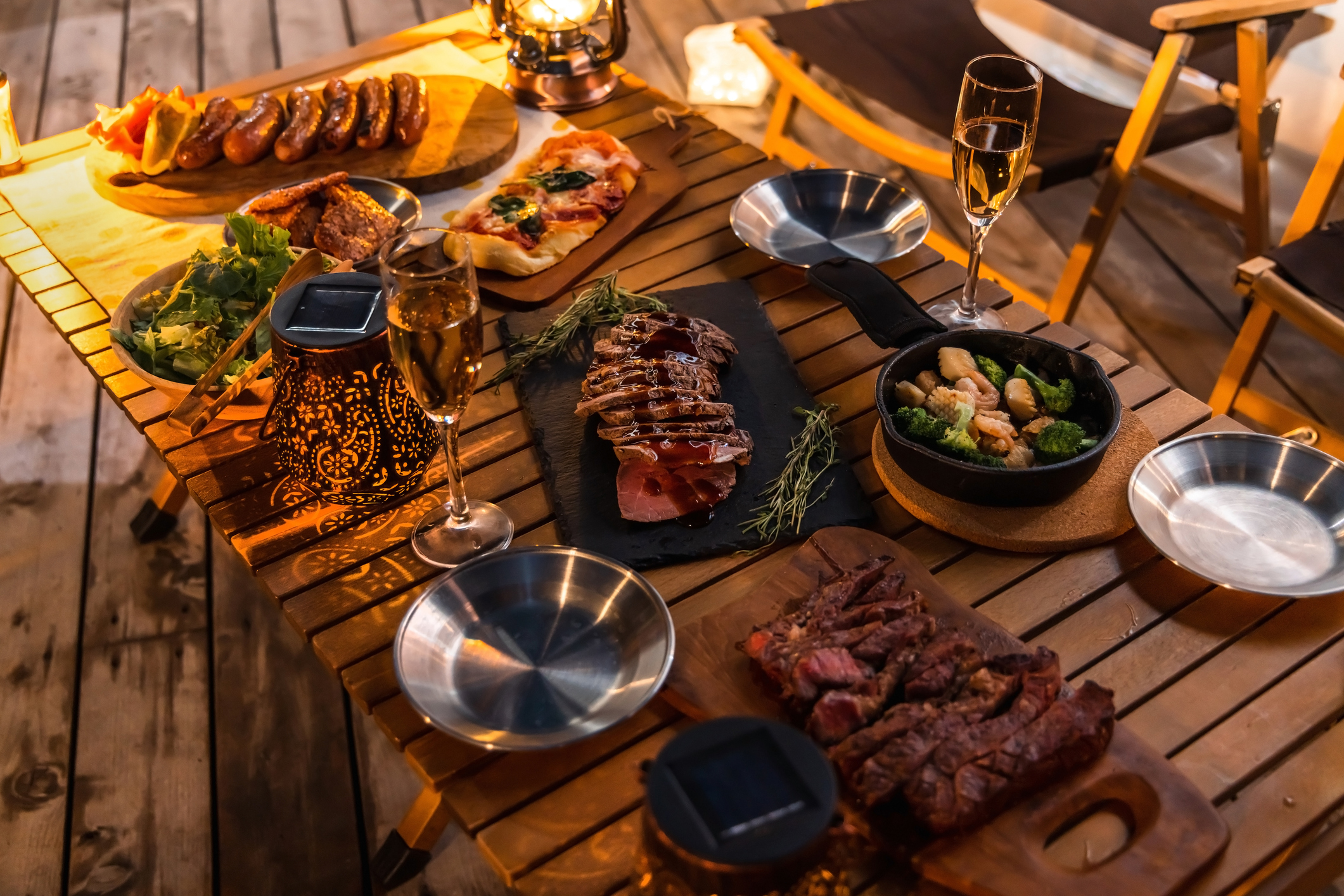 A wooden table loaded with different plates of red meat, bread and side dishes.