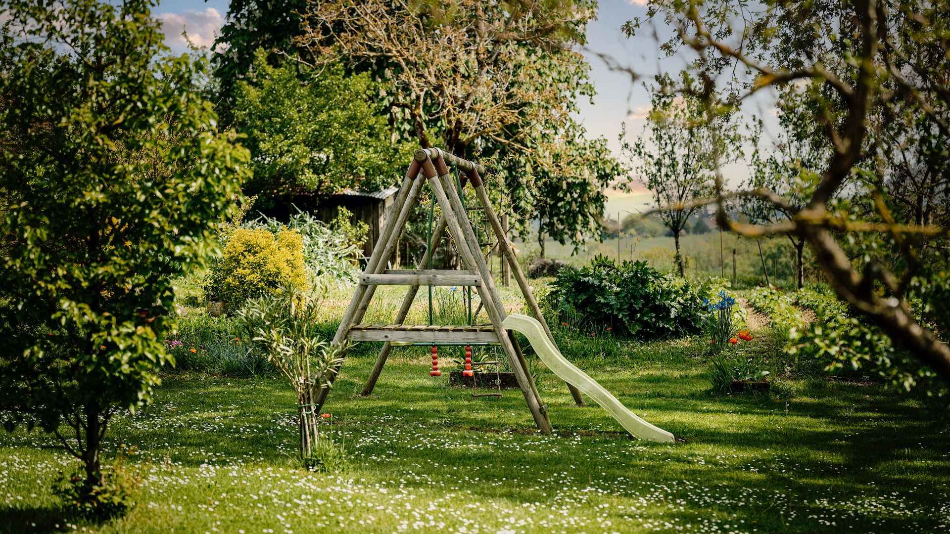 A wooden swing and green slide in a traditional garden in the countryside